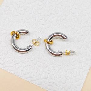 Macro detail of minimalist two-tone C-shape hoop earrings with golden butterfly backings