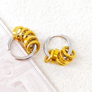Detail of silver hoop earrings with small gold rings showing interlocking metal textures