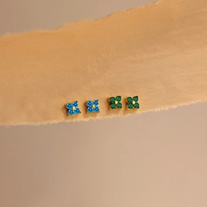 Detail von Kleeblatt-Ohrsteckern mit blauen und grünen Kristallen auf vergoldeter Basis
