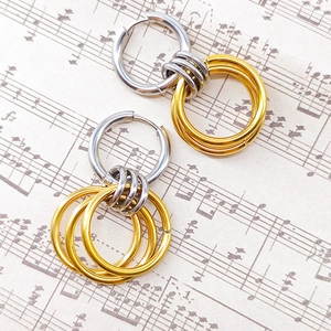 Detail of mixed-metal hoop earrings with gold rings on musical notes background