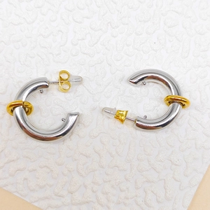 Close-up of chunky C-shape stainless steel earrings with sliding gold rings detail