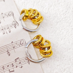 Two-tone stainless steel hoop earrings with gold rings on white fabric and sheet music