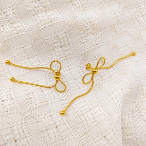 Detail view of golden bow earrings crafted with sleek snake chains and polished metal beads