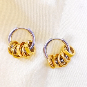 Detailed macro of two-tone 18K gold and stainless steel hoop earrings on silk