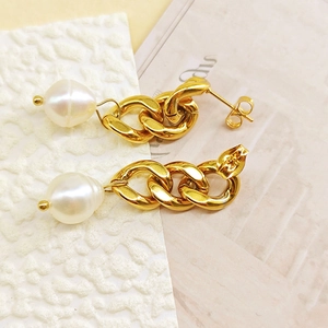 Détail de boucles d'oreilles chaîne dorée avec perles baroques et fermoirs papillon élégants