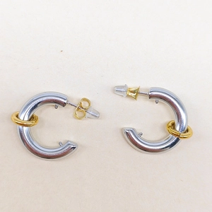 Detail of bicolor C-shape earrings with polished silver body and golden sliding ring element