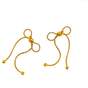 Macro detail of golden bow earrings made of sleek snake chain with decorative metal balls
