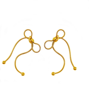 Detail showing gold bow earrings with snake chain texture and hanging tassels