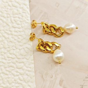 Gros plan de boucles d'oreilles chaînettes dorées avec perles baroques tombantes