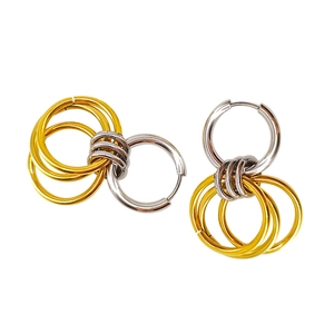 Detail of two-tone interlocking stainless steel hoop earrings with polished gold and silver