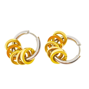 Close-up of two-tone stainless steel hoop earrings with sliding gold rings on silver