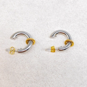 Detail of C-shaped mixed-metal earrings in silver with gold accent rings and butterfly backings