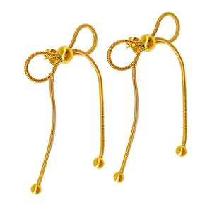 Detailed macro view of golden bow earrings featuring long snake chains and polished beads