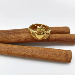 Gros plan d'une bague Claddagh dorée avec cœur et couronne sur bâtons de cannelle