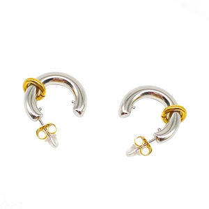 Detailed macro view of two-tone stainless steel C-shape earrings with gold and silver finish