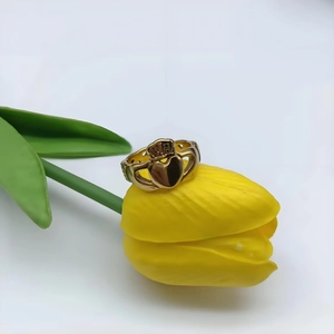Gros plan d'une bague Claddagh dorée avec cœur et couronne sur des tulipes jaunes