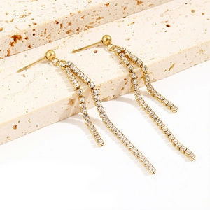 Detailed view of long gold tassel earrings with shimmering cubic zirconia chains on stone