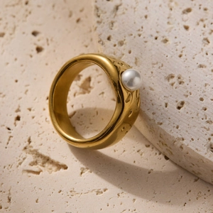 Golden liquid lava ring with baroque pearl on natural travertine stone background