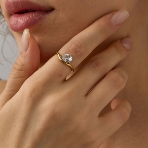 Bague élégante en or avec zircon de forme poire portée par un mannequin femme