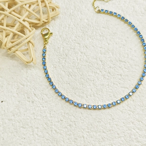Close-up of gold tennis bracelet with light blue cubic zirconia and lobster clasp