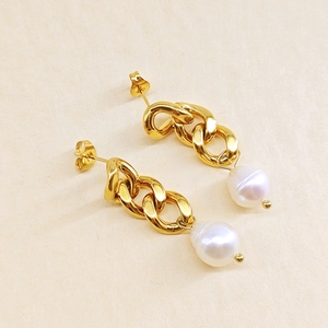 Détail de boucles d'oreilles chaîne dorées avec pendentifs en perles blanches