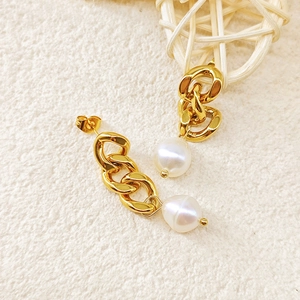 Gros plan de boucles d'oreilles chaînes dorées avec perle baroque blanche pendante