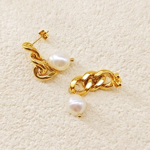 Détail de boucles d'oreilles vintage chaînées en or avec perles blanches