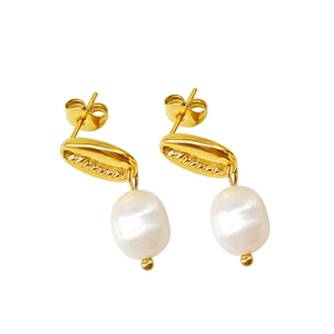 Détail macro des boucles d'oreilles coquillage doré avec perles blanches en goutte