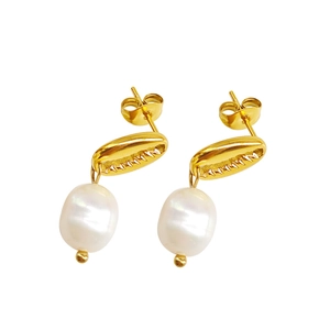 Gros plan de boucles d'oreilles coquillage doré avec perles blanches sur fond blanc