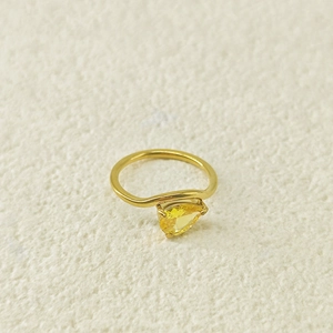 Vue détaillée d'une bague dorée ondulée avec une pierre précieuse jaune en forme de poire