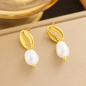 Détails de boucles d'oreilles perles baroques dorées montrant le travail précis du métal