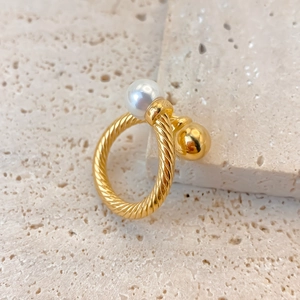 Detail of twisted gold ring featuring a white pearl and polished metallic bead