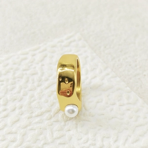 Macro view of gold plated liquid lava ring with a white baroque pearl on a textured background
