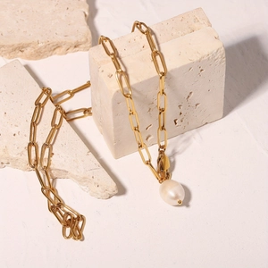 Golden paperclip chain necklace with a baroque freshwater pearl pendant on stone