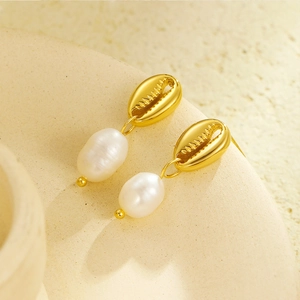 Détails de boucles d'oreilles coquillage dorées avec perles blanches sur présentoir