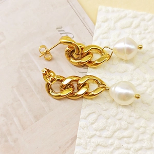 Boucles d'oreilles chaîne dorée avec perles baroques blanches sur fond élégant texturé