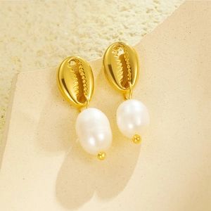 Gros plan de boucles d'oreilles coquillage doré avec d'élégantes perles blanches