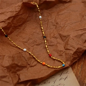 Macro detail of gold beaded chain necklace with colorful beads on vintage paper