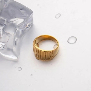 Macro shot of gold croissant textured ring on a minimalist white background with ice cubes