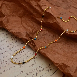 Close-up of golden beaded necklace with colorful resin beads on vintage paper