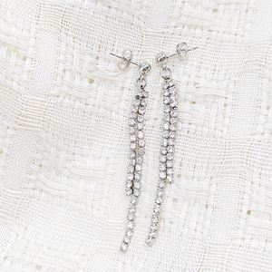 Close-up of elegant double-row zircon tassel drop earrings on white lace fabric