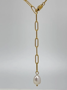 Detail view of a gold paperclip chain necklace featuring a white freshwater pearl pendant