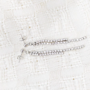 Detail view of long silver tassel earrings with double-row cubic zirconia on woven fabric
