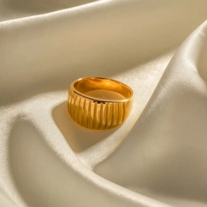 Close-up of golden ribbed croissant ring texture on elegant cream silk background