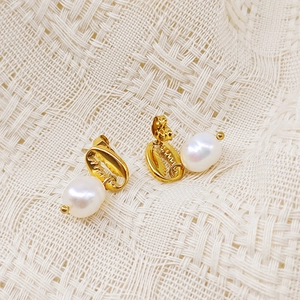 Détail des boucles d'oreilles coquillage doré avec perles irisées sur un tissu en résille