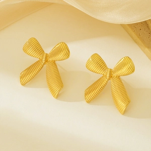 Detail of 18k gold plated stainless steel bow earrings with brushed metal texture