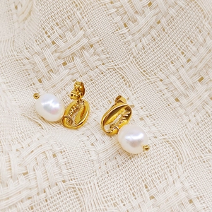 Gros plan de boucles d'oreilles coquillage doré avec perles blanches sur texture