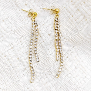 Detailed close-up of long tassel earrings with sparkling cubic zirconia on white fabric