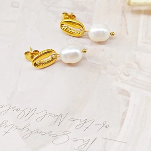 Détail de boucles d'oreilles coquillage dorées avec perles blanches lustrées