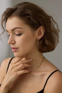 Détail de boucles d'oreilles pendantes et collier avec pierres de zircon violettes sur un modèle